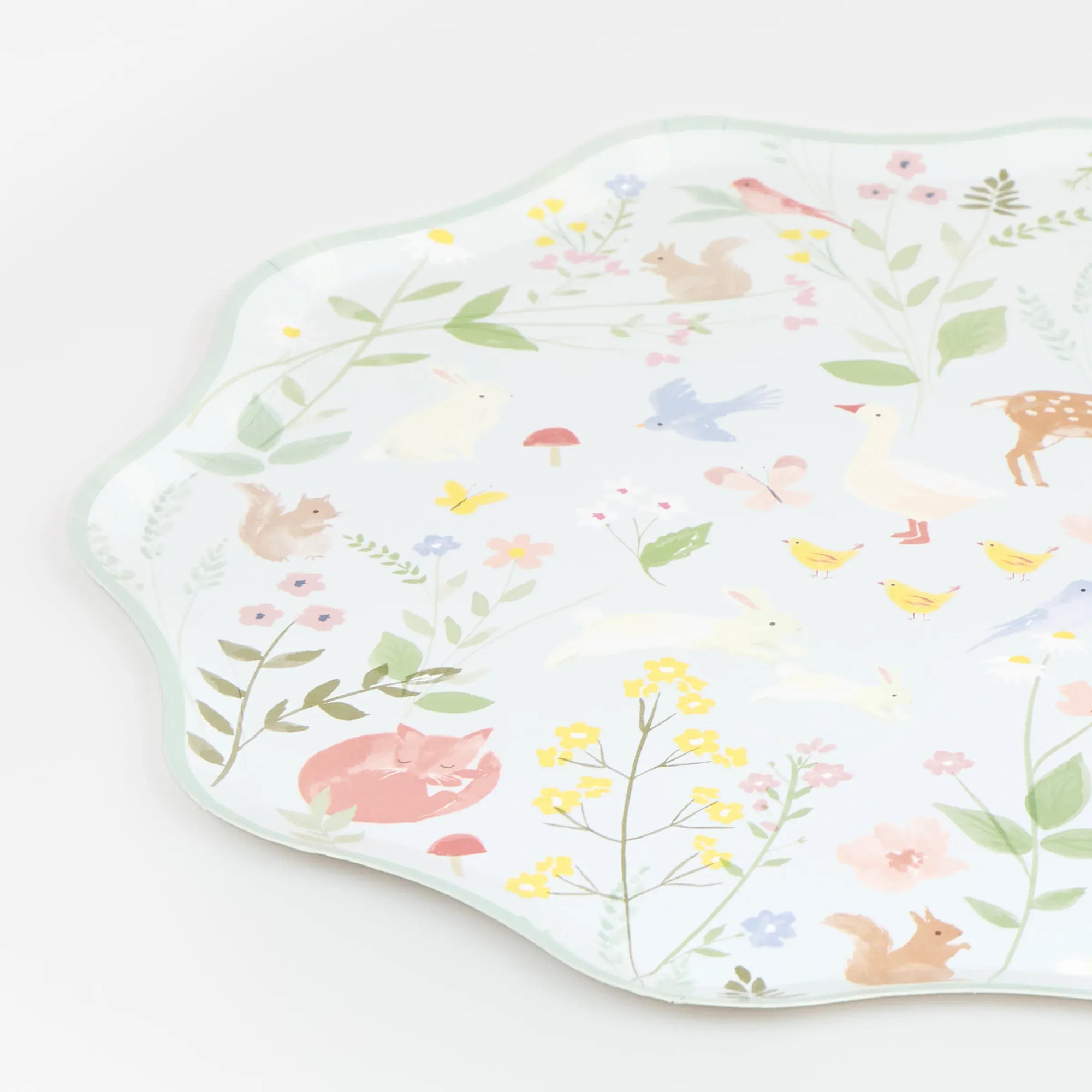 Close up of mint Meri Meri Little Animals party paper plate with waved edge, watercolour bunnies, fox and wildflowers