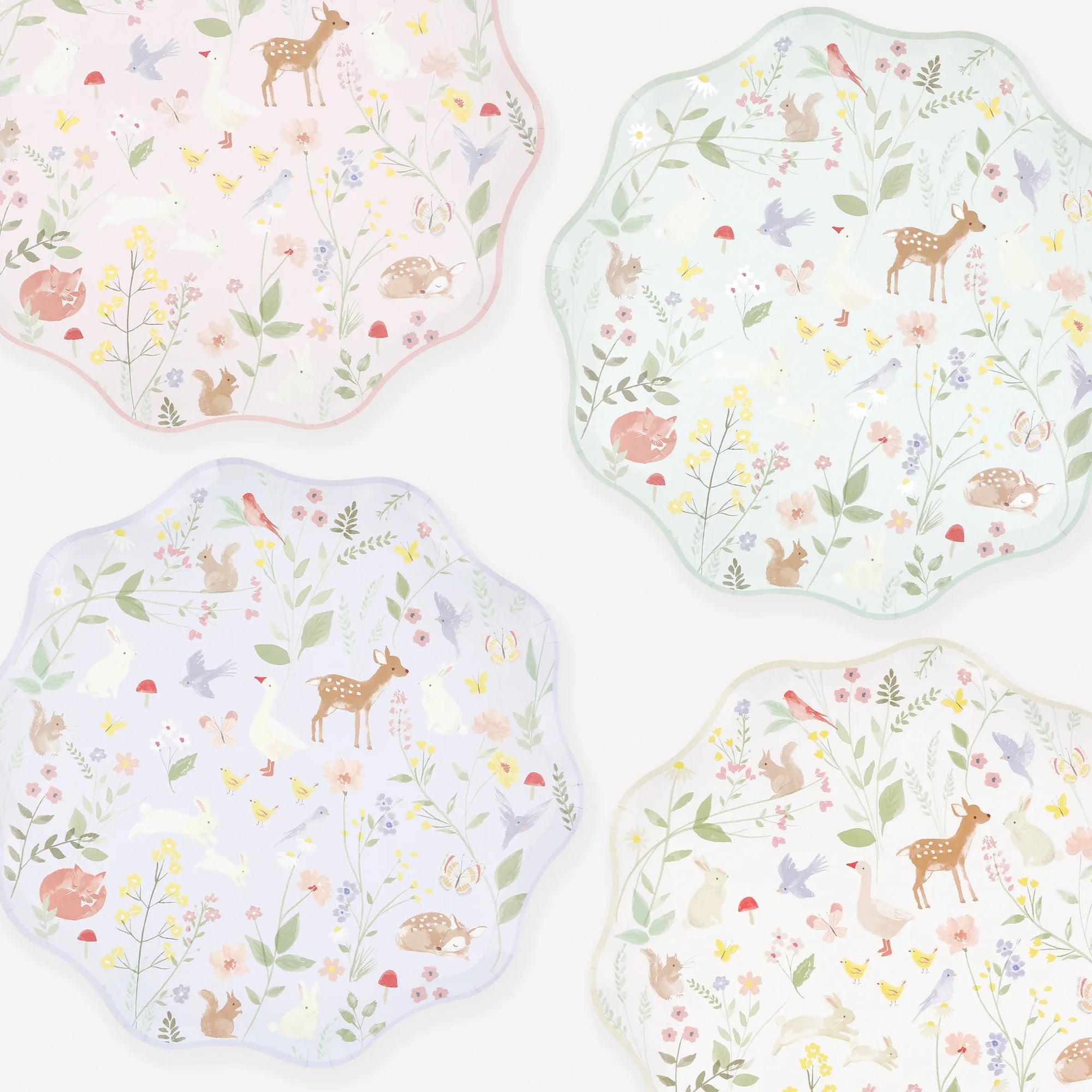 Meri Meri Little Animals plates in pink, mint, lavender and cream pastel watercolour woodland prints.  Four scalloped-edge decorative plates arranged on a white background, each with a pastel woodland print featuring deer, birds, flowers, and leaves in soft pink, mint, lavender, and pale blue tones.